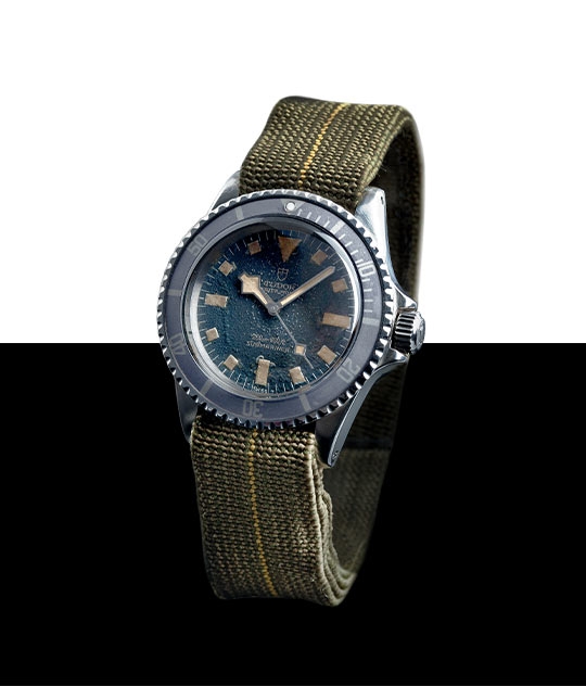 1977年帝舵oyster prince submariner「MARINE NATIONALE」9401 海軍潛水員常使用降落傘安全帶來製作錶帶，而這款於1977年問世的型號9401腕錶便是當中的範例。這種物料充滿彈性，佩戴非常舒適，即使身穿潛水衣時也易於調校。此腕錶背面鐫刻「M.N. 77」字樣。 圖示的錶帶並非由帝舵表生產。